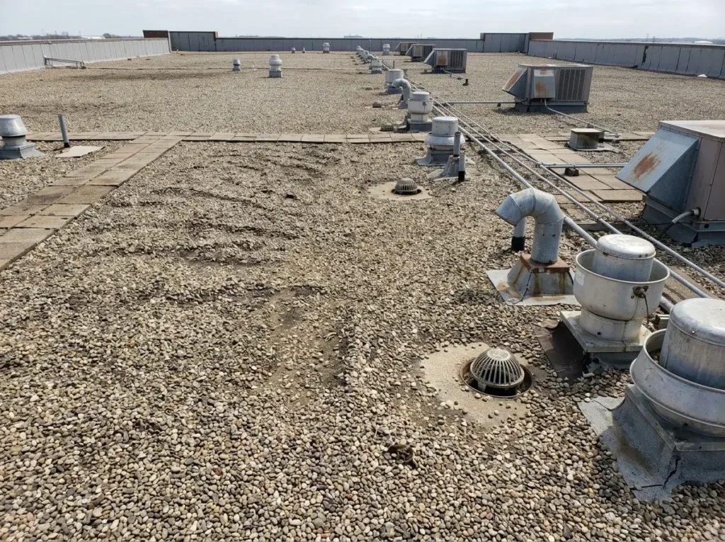 Gravel surfaced built-up roof on a warehouse with rooftop vents and drains