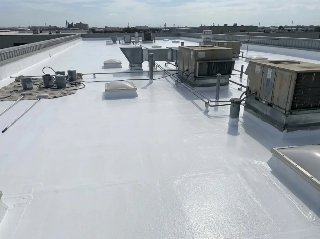 : Freshly applied white silicone roof coating on a commercial flat roof with rooftop units